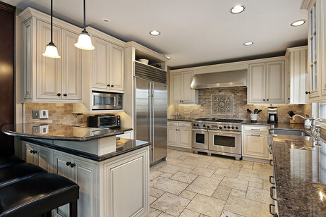 A large kitchen with granite countertops, stainless steel appliances, and tile floors. The kitchen features white and gray colors.