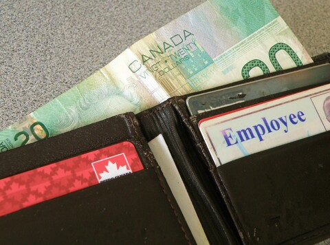 A black wallet containing three cards and two twenty dollar bills.