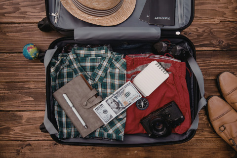 A well packed suitcase containing clothing, money and shoes 