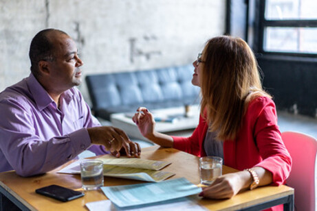 Two people talking to each other at a table.