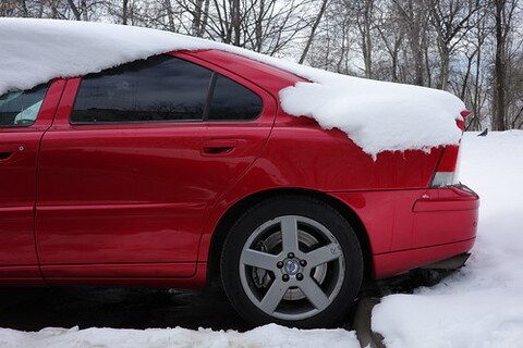 A red car parked in a parking lot during the winter season.