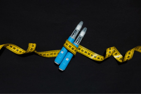 A pair of Ozempic pens, wrapped in measuring tape.
