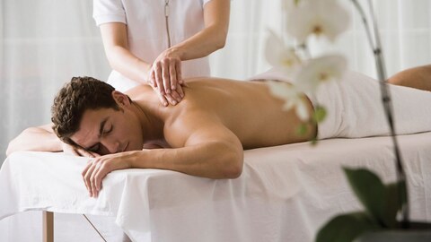 A man is receiving a spa treatment in a massage chair.