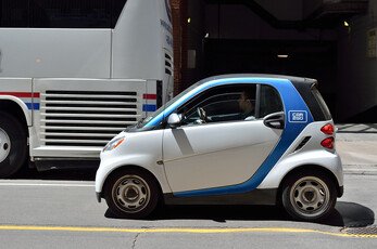A small car from a European car sharing fleet driving in the city.