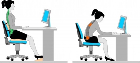A woman is working on a computer in a gray chair.