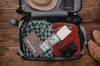 A well packed suitcase containing clothing, money and shoes 