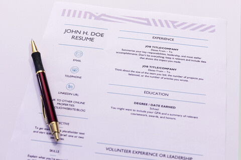 A ballpoint pen lying on top of a sample resume.