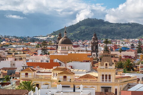 The image depicts a city with a beautiful view of a hill in the background, along with various buildings, including churches, located in the foreground. The city is characterized by its many church buildings, and the town's architecture appears to be from the 16th century. The scene captures the essence of a historic cityscape with a mix of both old and new structures, creating an aesthetically pleasing image.