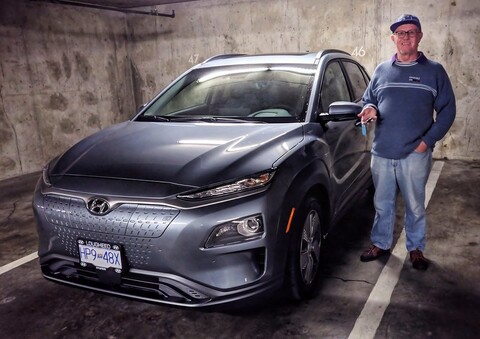 A man standing next to a gray Hyundai KONA Electric in an underground car park