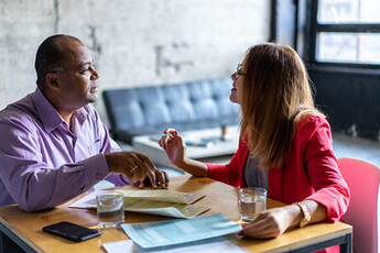 Two people talking to each other at a table.