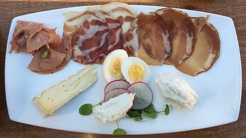 A plate full of different types of food, including cheese, eggs, meat, and vegetables.