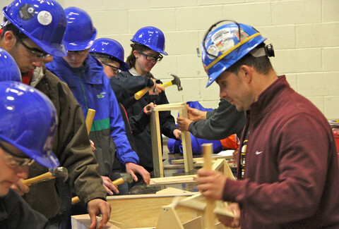 A man in a blue safety helmet is using a hammer to fix something.