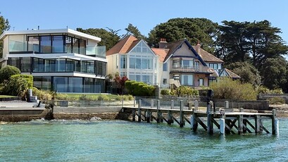 A pier in front of a house near the ocean.