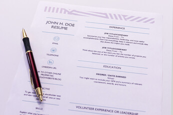 A ballpoint pen lying on top of a sample resume.