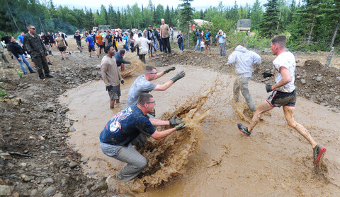 A group of people standing and playing in the mud, some of them holding shovels.