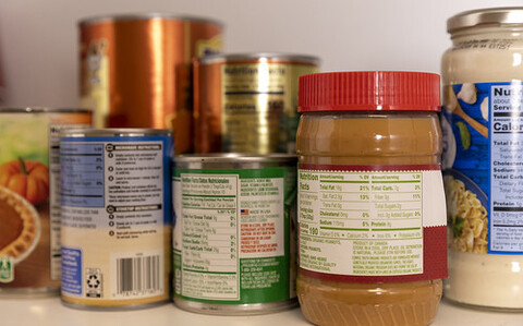 Several different food items are lined up, including canned food and jars of jam.