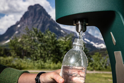 A bottle of water is being poured out of a vending machine.