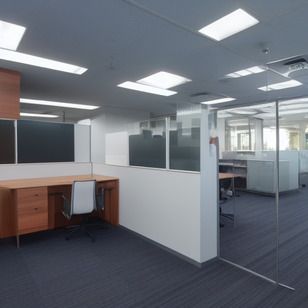 A large office with several monitors and chairs is clean and ready for work.